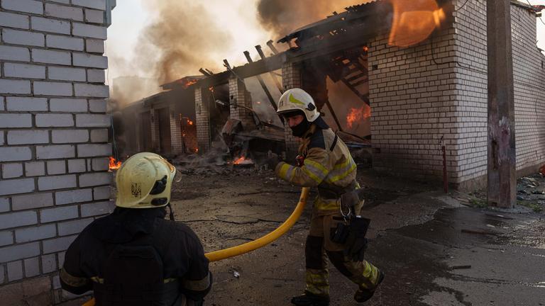 Rettungskräfte löschen in Kiew ein Feuer in einer Autowerkstatt, die durch einen russischen Angriff beschädigt wurde. 