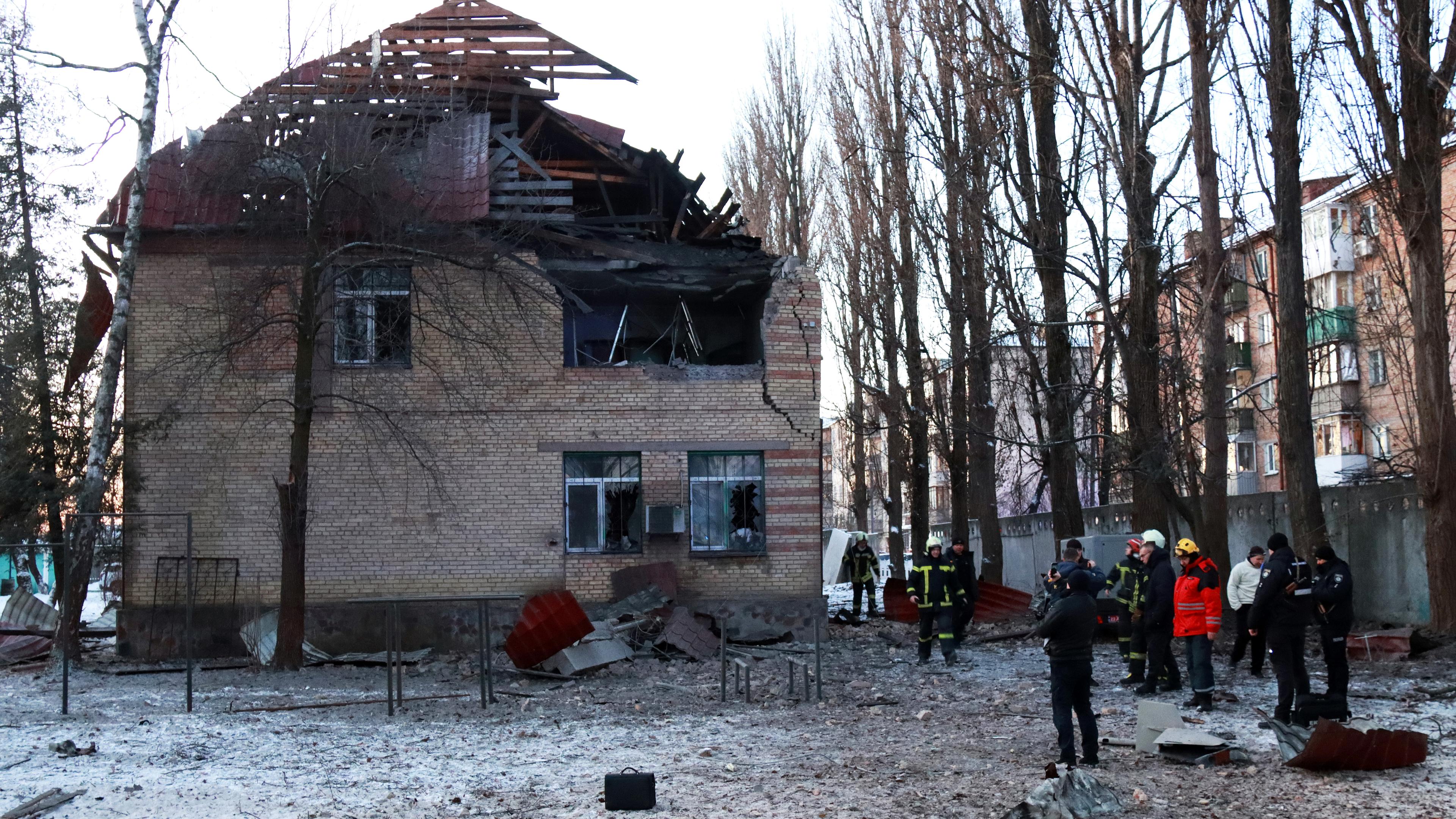 Kiew: Rettungskräfte stehen in der Nähe eines Hauses, das durch Teile einer abgeschossenen Drohne beschädigt wurde. (14.12.2022)