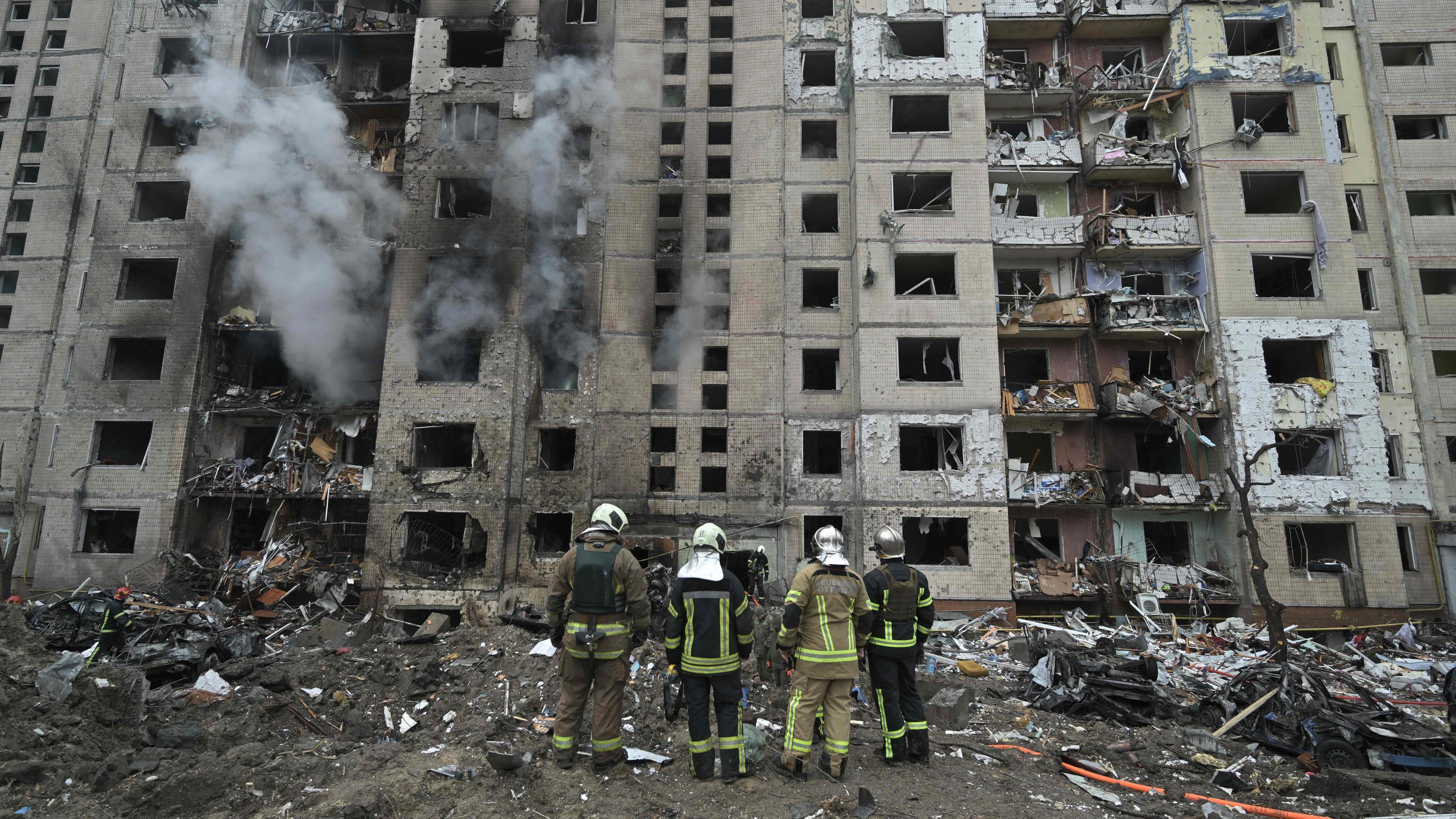 Feuerwehrleute stehen vor einem zerstörten Gebäude in Kiew.