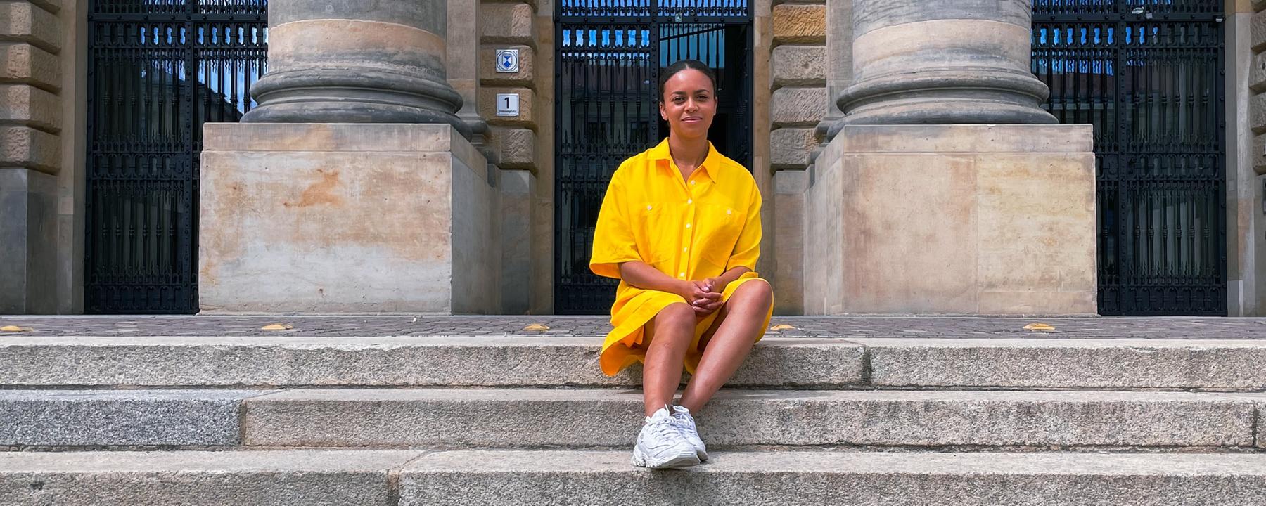 Aminata sitzt auf einer steinernen Treppe. 