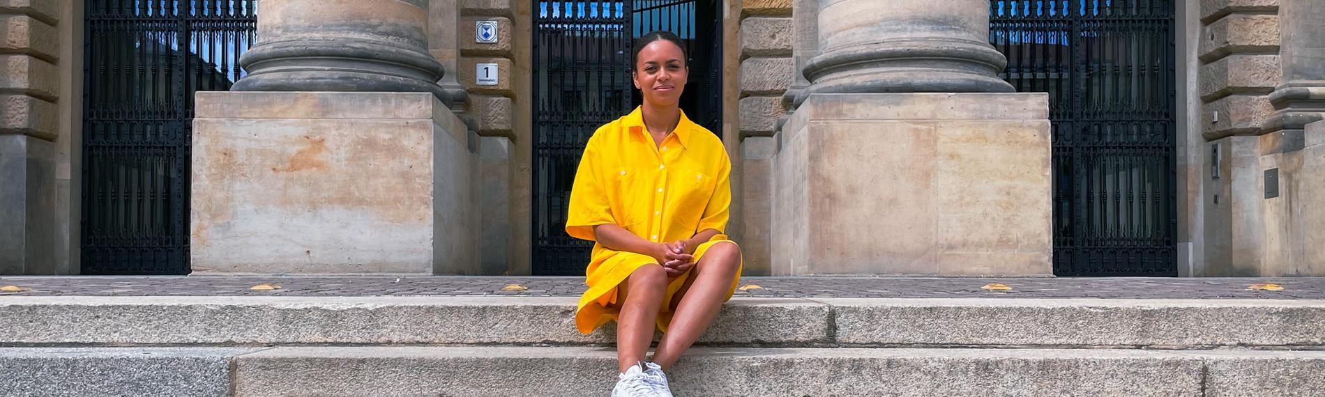 Aminata sitzt auf einer steinernen Treppe. 