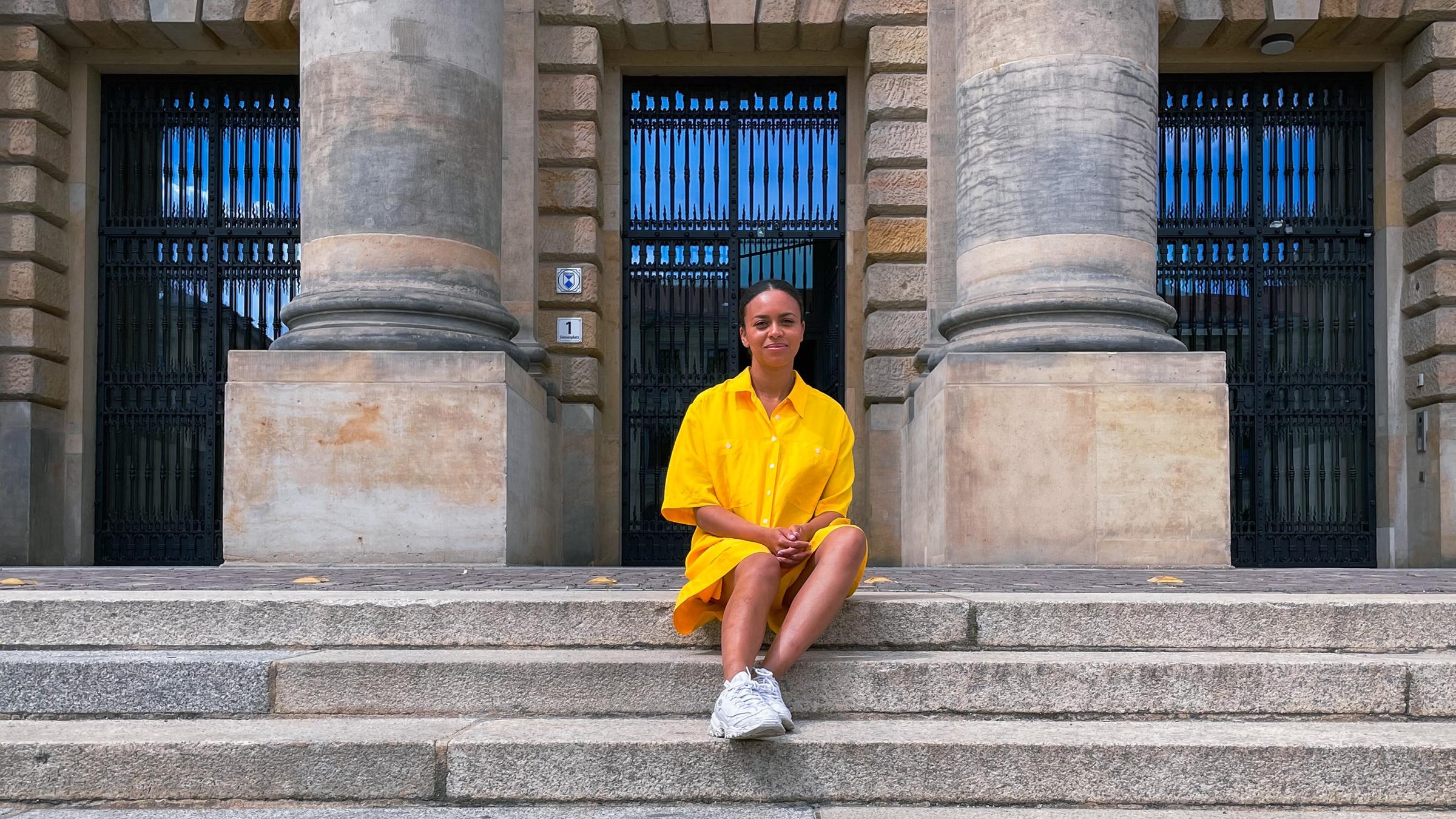 Aminata sitzt auf einer steinernen Treppe. 