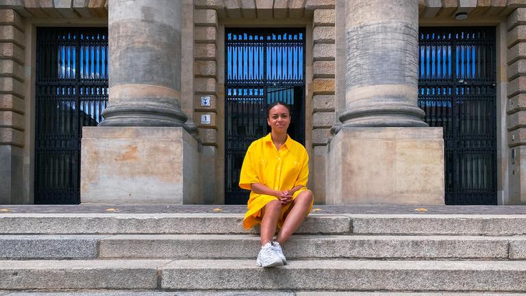 Aminata sitzt auf einer steinernen Treppe. 