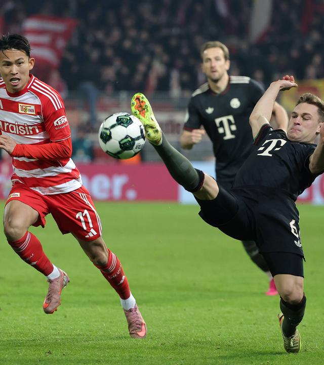 Joshua Kimmich streckt im Zweikampf mit Union Berlins Jeong Woo-yeong seinen Fuß in Richtung Ball