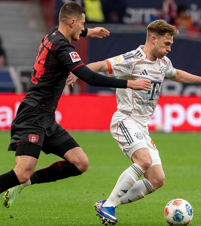 Leverkusens Mittelstürmer Patrick Schick packt Bayerns Mittelfeldspieler Joshua Kimmich von hinten an