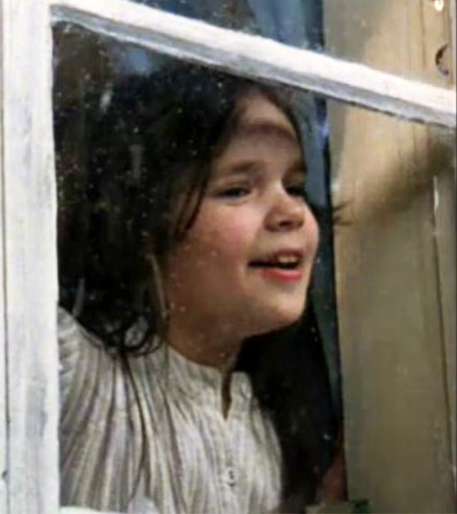 Die Kinder sind aufgewacht, schauen aus dem Fenster und sehen den ersten Schnee fallen.