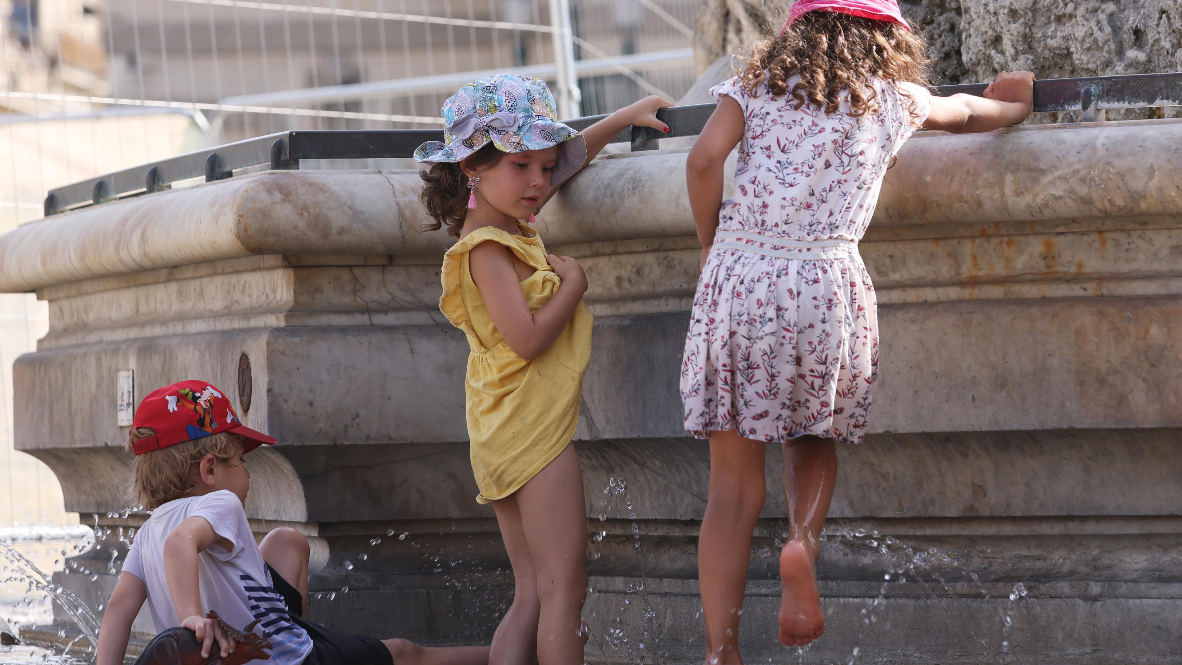 Kinder kühlen sich bei 38 Grad Celsius am Brunnen der Trois Graces auf dem Place de Comedie ab. 