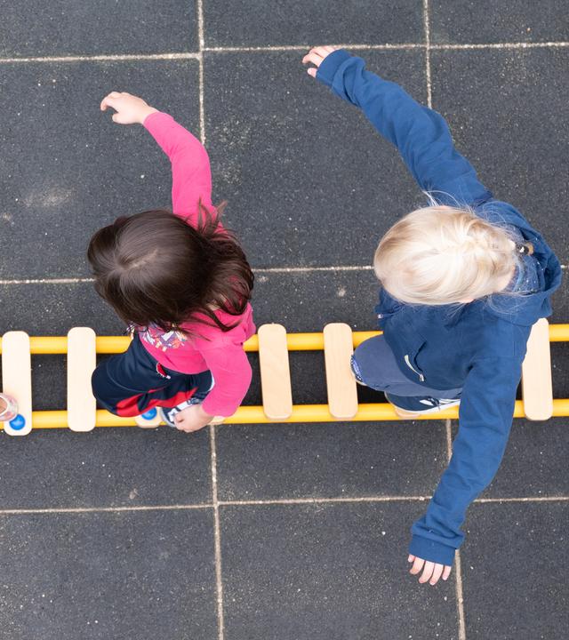 Drei Kinder balancieren auf einem Spielplatz