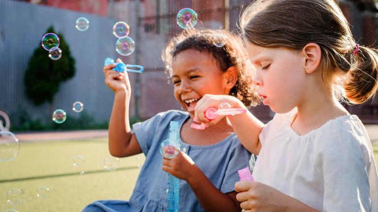Zwei junge Mädchen blasen Seifenblasen 