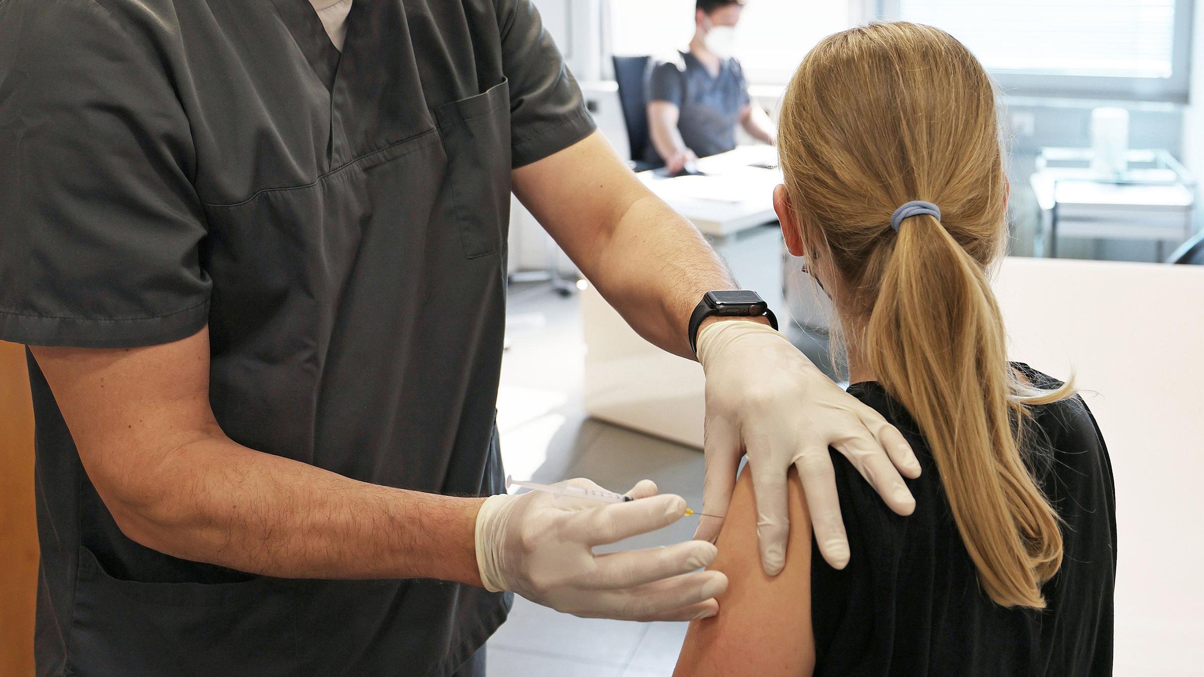 A twelve-year-old girl is vaccinated by the family doctor