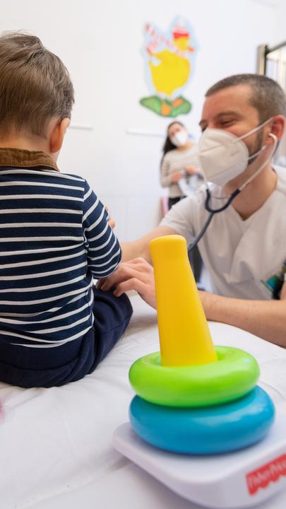 Ein Arzt untersucht in einer Kinderklinik ein Kind.