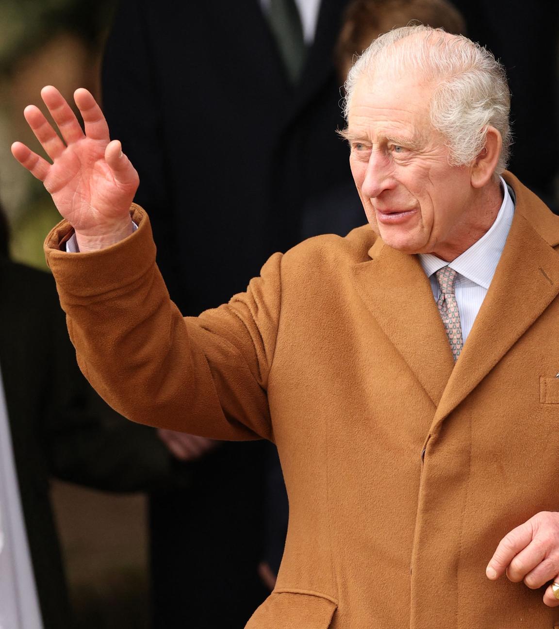König Charles steht im Freien und winkt zu umstehenden Personen