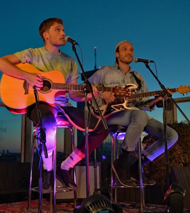 Die Musiker Stfan und Michael Heinrich von KLAN bei einem Open-Air-Konzert über den Dächern von Berlin