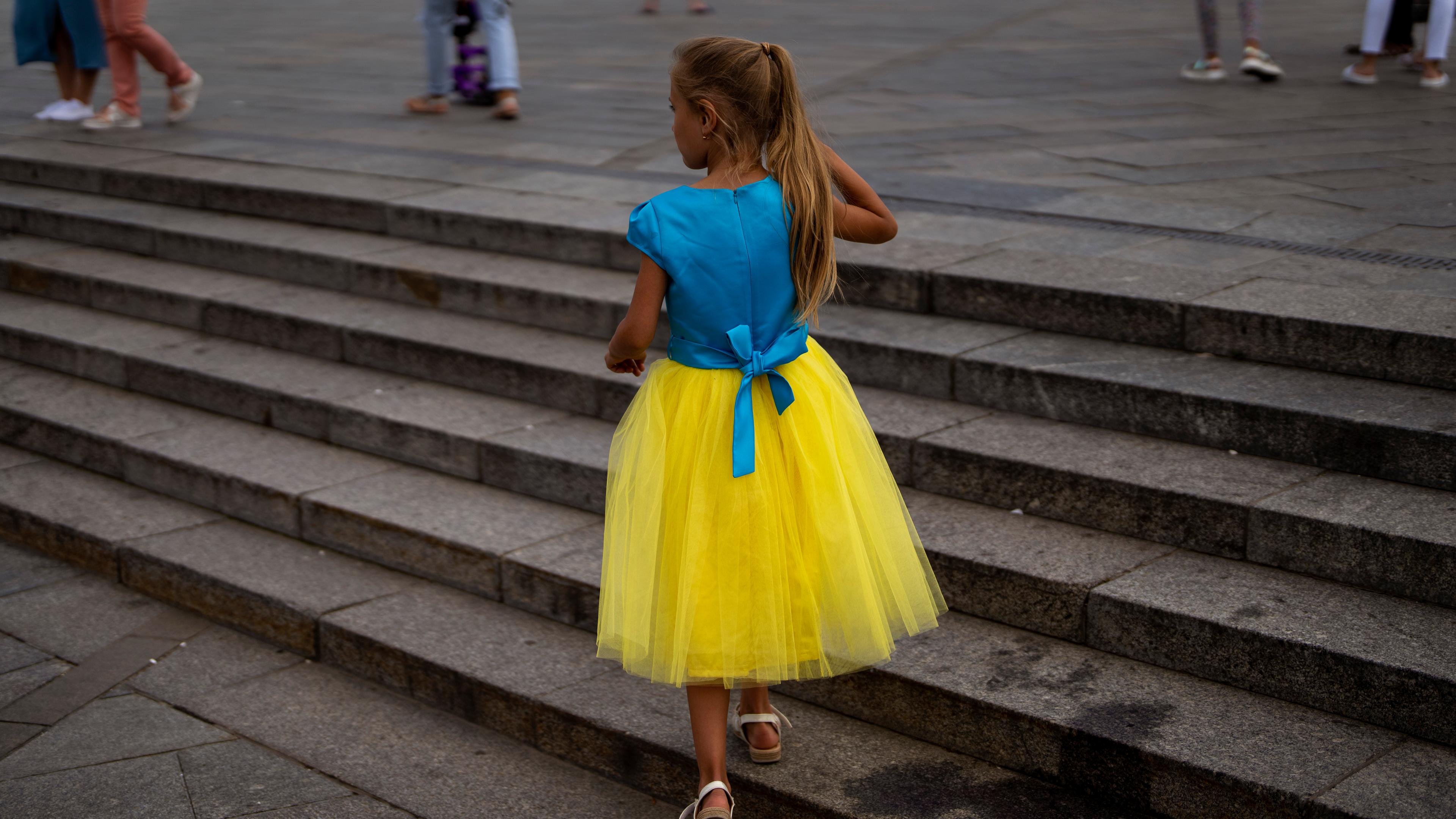 Mädchen in blau-gelbem Kleid läuft eine Treppe hoch