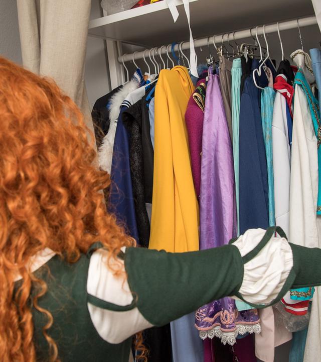 Eine junge Frau schaut in ihren Kleiderschrank.