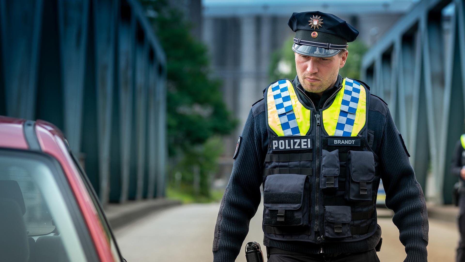 Nick (Raúl Richter) schaut sich einen Pkw am Straßenrand näher an.