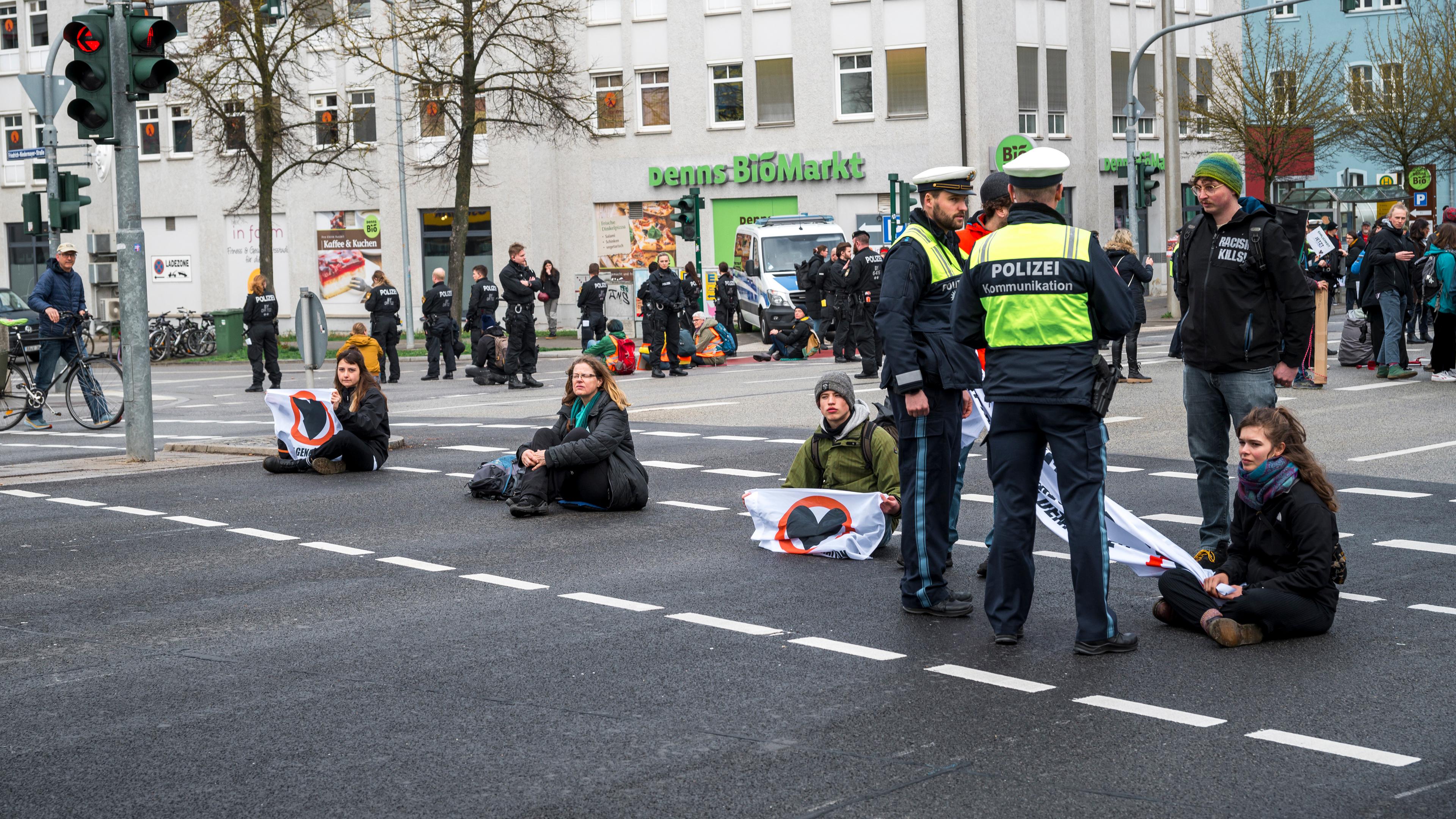Demonstrantinnen und Demonstranten blockieren eine Kreuzung in Regensburg