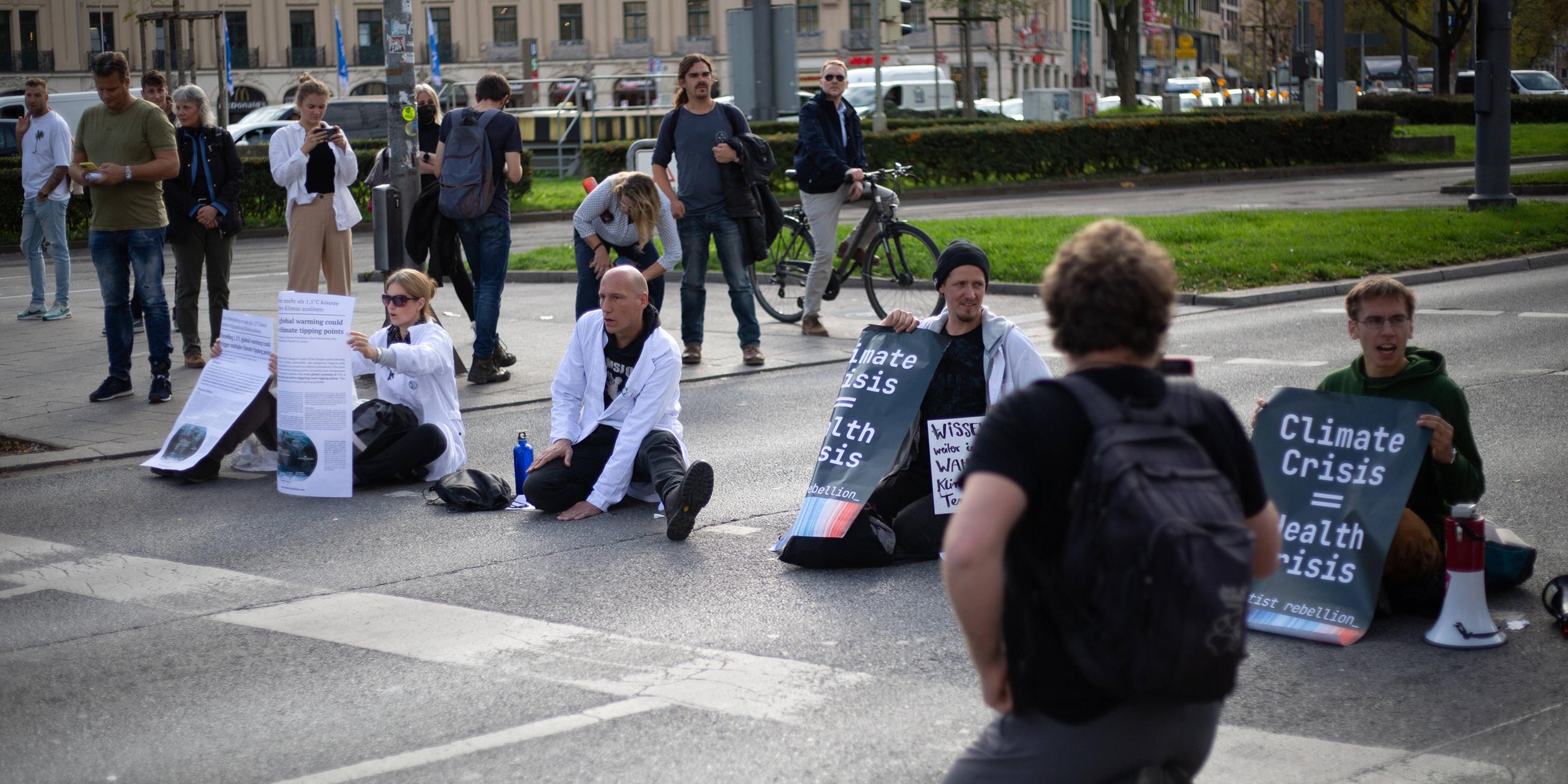 Klima-Aktivisten um Jörg Alt kleben sich auf die Karlsstraße in München