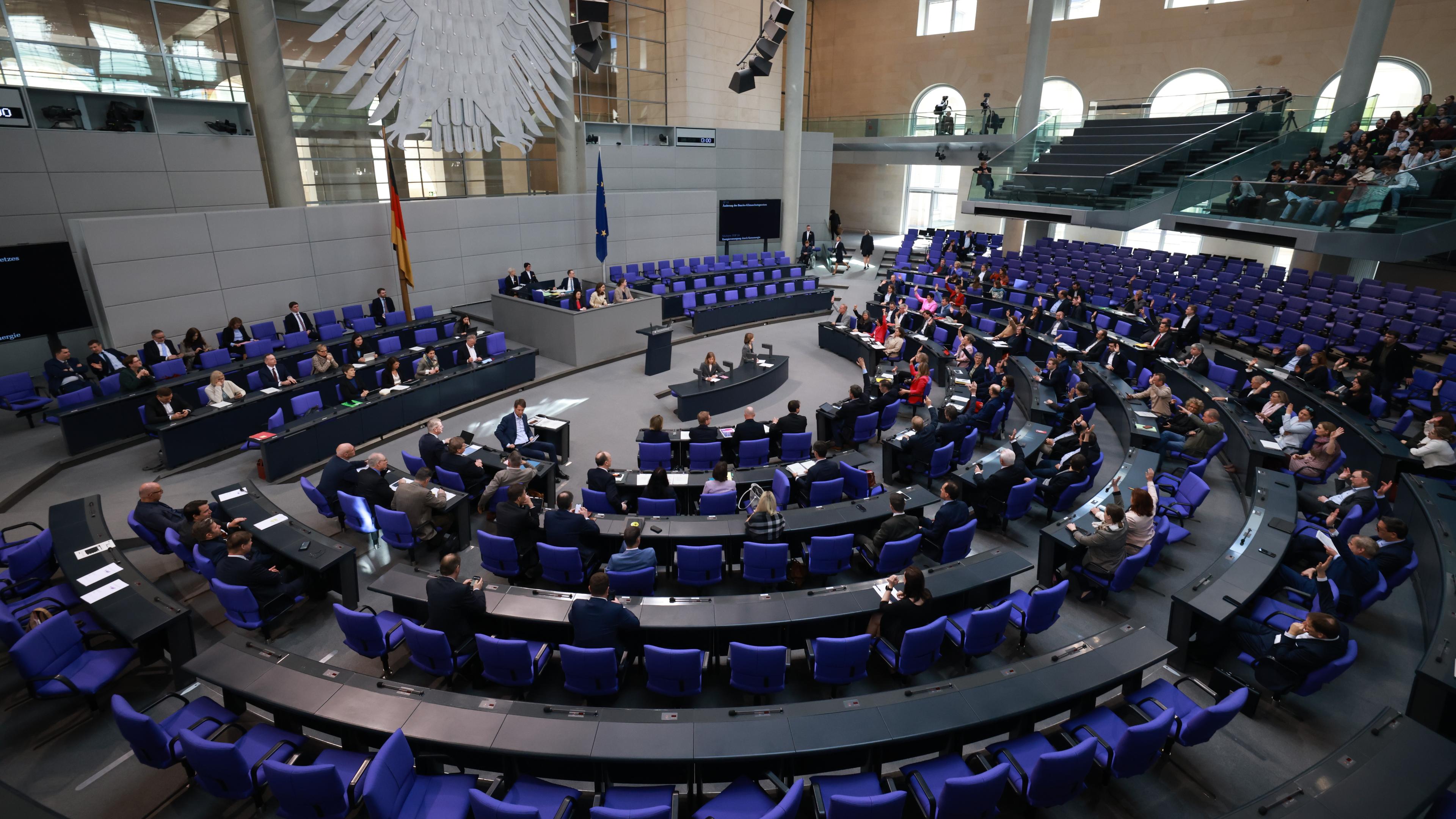 Mitglieder des Bundestags heben ihre Hände während einer Abstimmung.