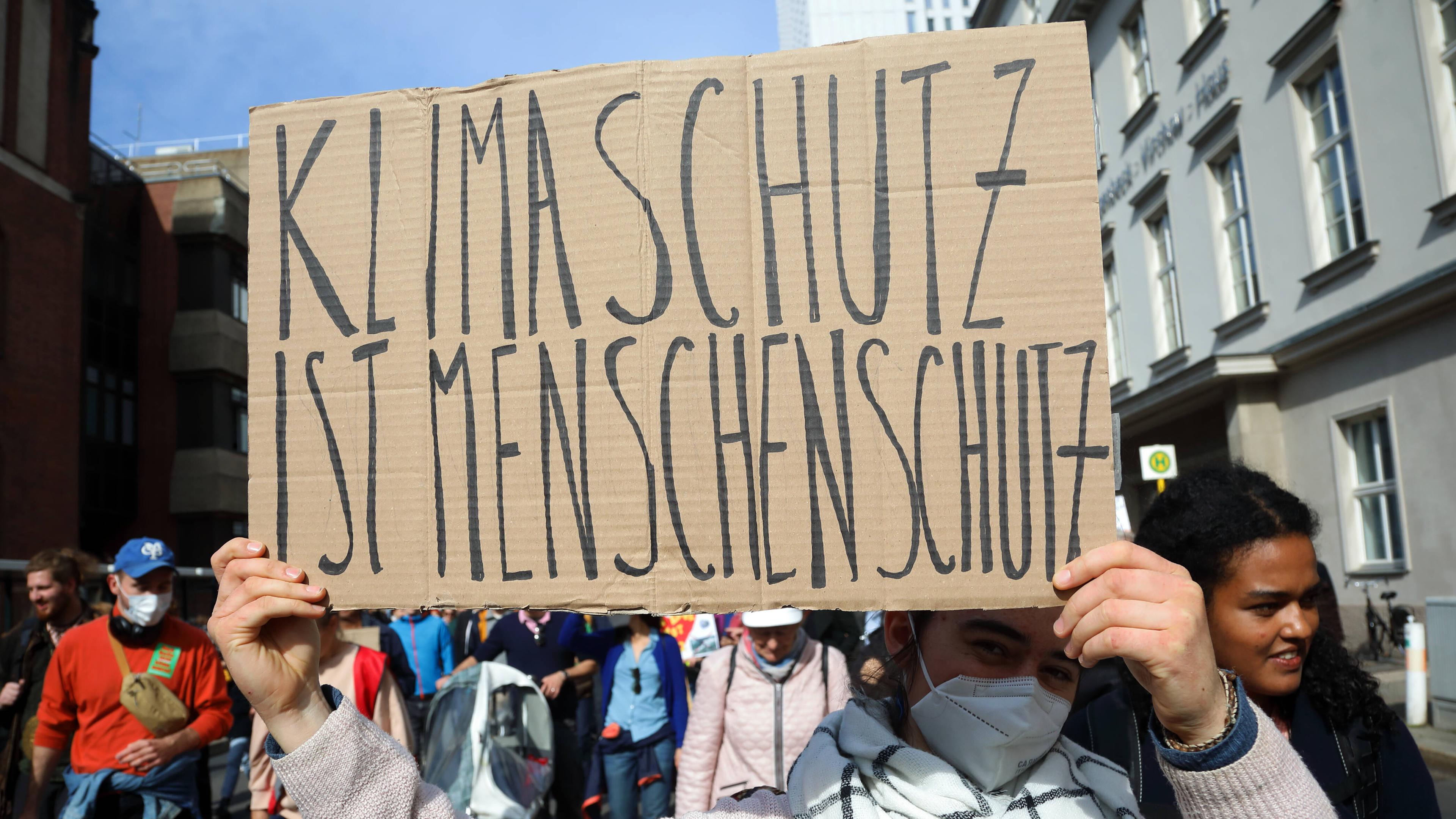 Demonstranten mit Schild mit Aufschrift "Klimaschutz ist Menschenschutz"