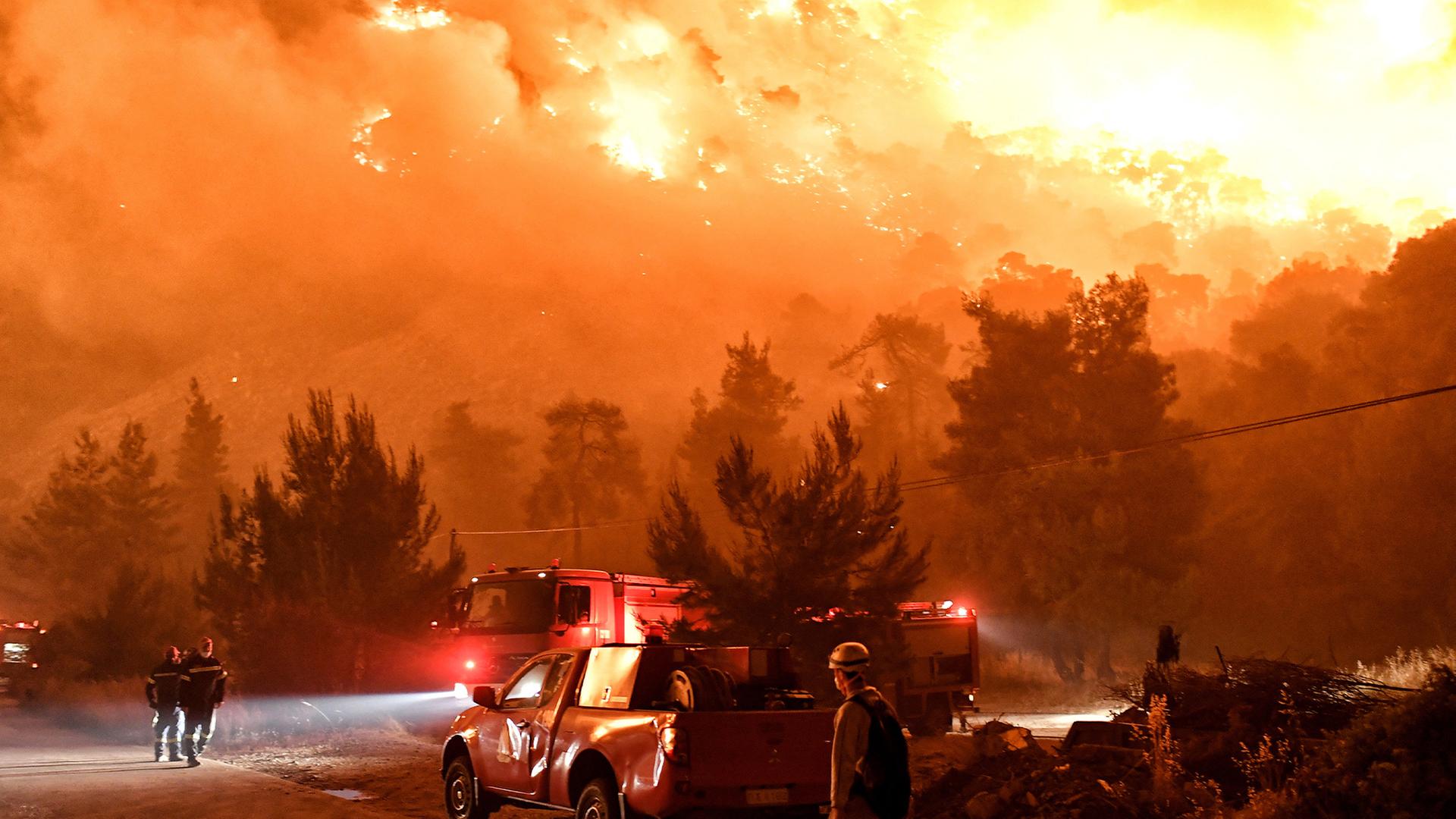 Zu sehen sind Feuerwehrmänner, die einen Waldbrand in Griechenland bekämpfen. 