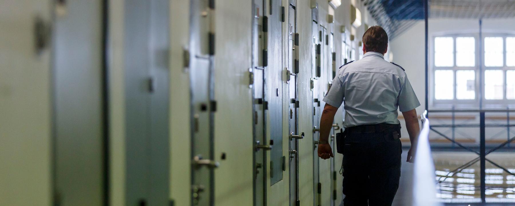 Ein Vollzugsbeamter geht während einem Kontrollgang in der Justizvollzugsanstalt in Bruchsal an den Zellentüren der Insassen vorbei.