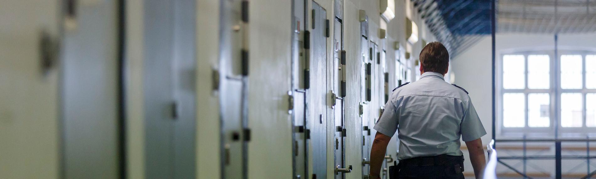 Ein Vollzugsbeamter geht während einem Kontrollgang in der Justizvollzugsanstalt in Bruchsal an den Zellentüren der Insassen vorbei.