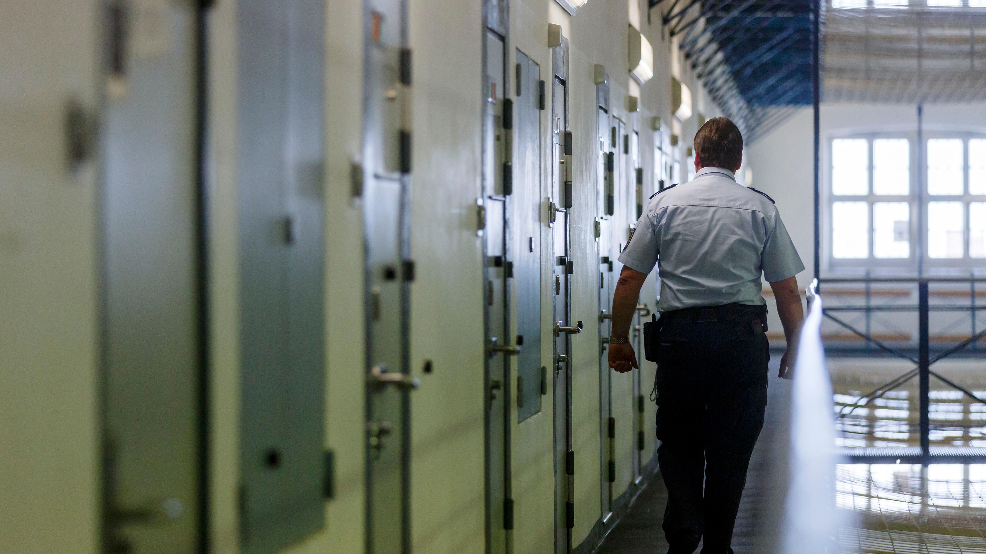 Ein Vollzugsbeamter geht während einem Kontrollgang in der Justizvollzugsanstalt in Bruchsal an den Zellentüren der Insassen vorbei.