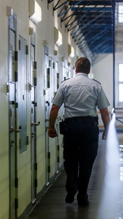 Ein Vollzugsbeamter geht während einem Kontrollgang in der Justizvollzugsanstalt in Bruchsal an den Zellentüren der Insassen vorbei.