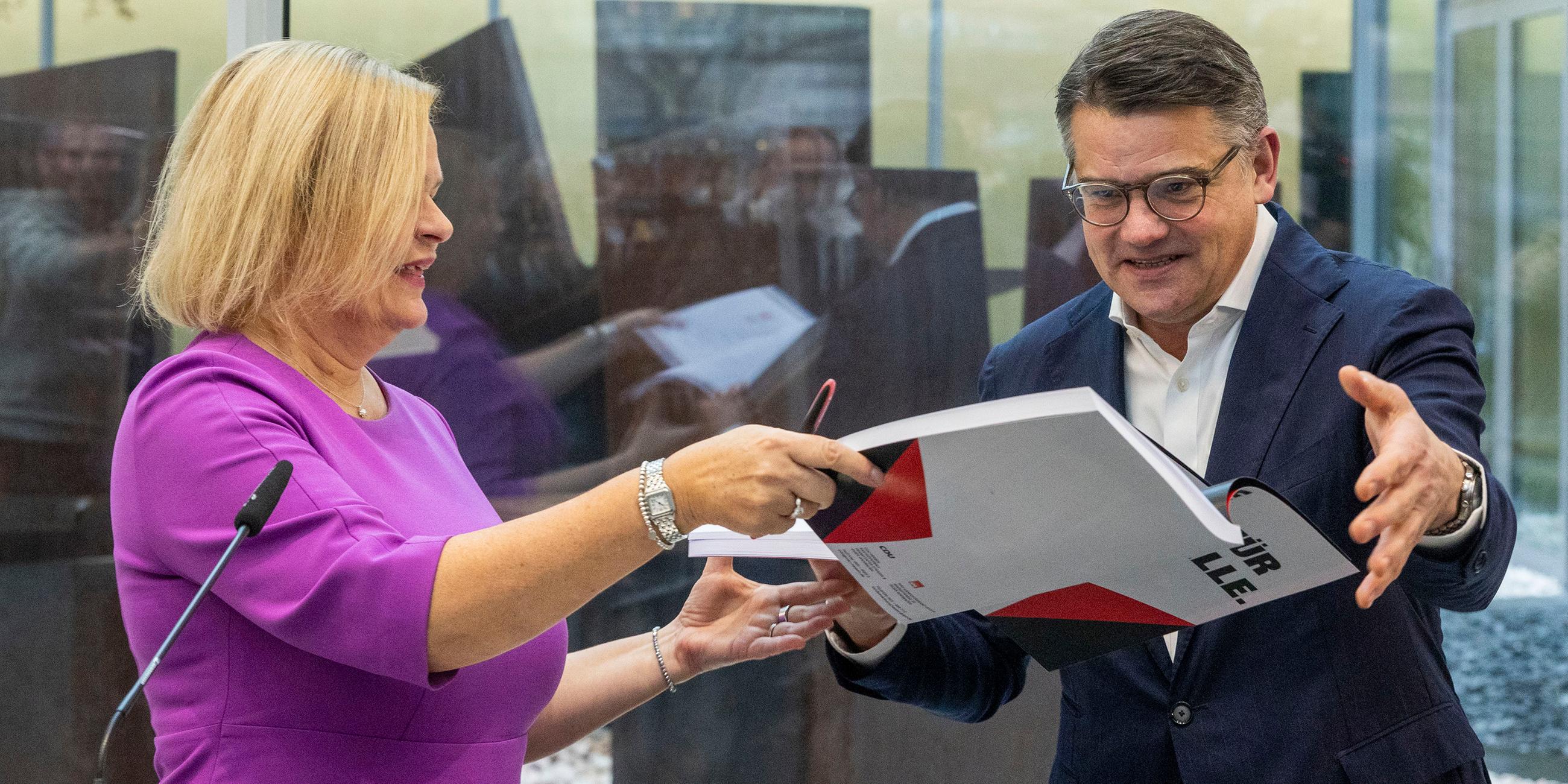 Nancy Faeser und Boris Rhein tauschen den Koalitionsvertrag der zukünftigen hessischen Landesregierung von SPD und CDU aus