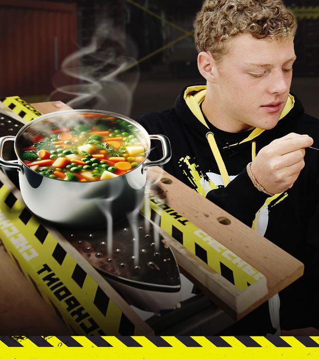Checkpoint: In einen Werkstatt-Tisch sind hintereinander zwei Bügeleisen eingeklemmt, deren Fuß nach oben zeigt und auf denen ein dampfender Topf steht. Kenneth kniet vor dem Tisch und füttert Moderator Tommy Scheel mit einem Löffel. 