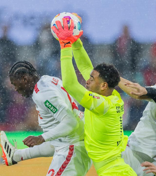 Freiburgs Torwart Noah Atubolu kommt vor Kölns Faride Alidou (l) an den Ball.