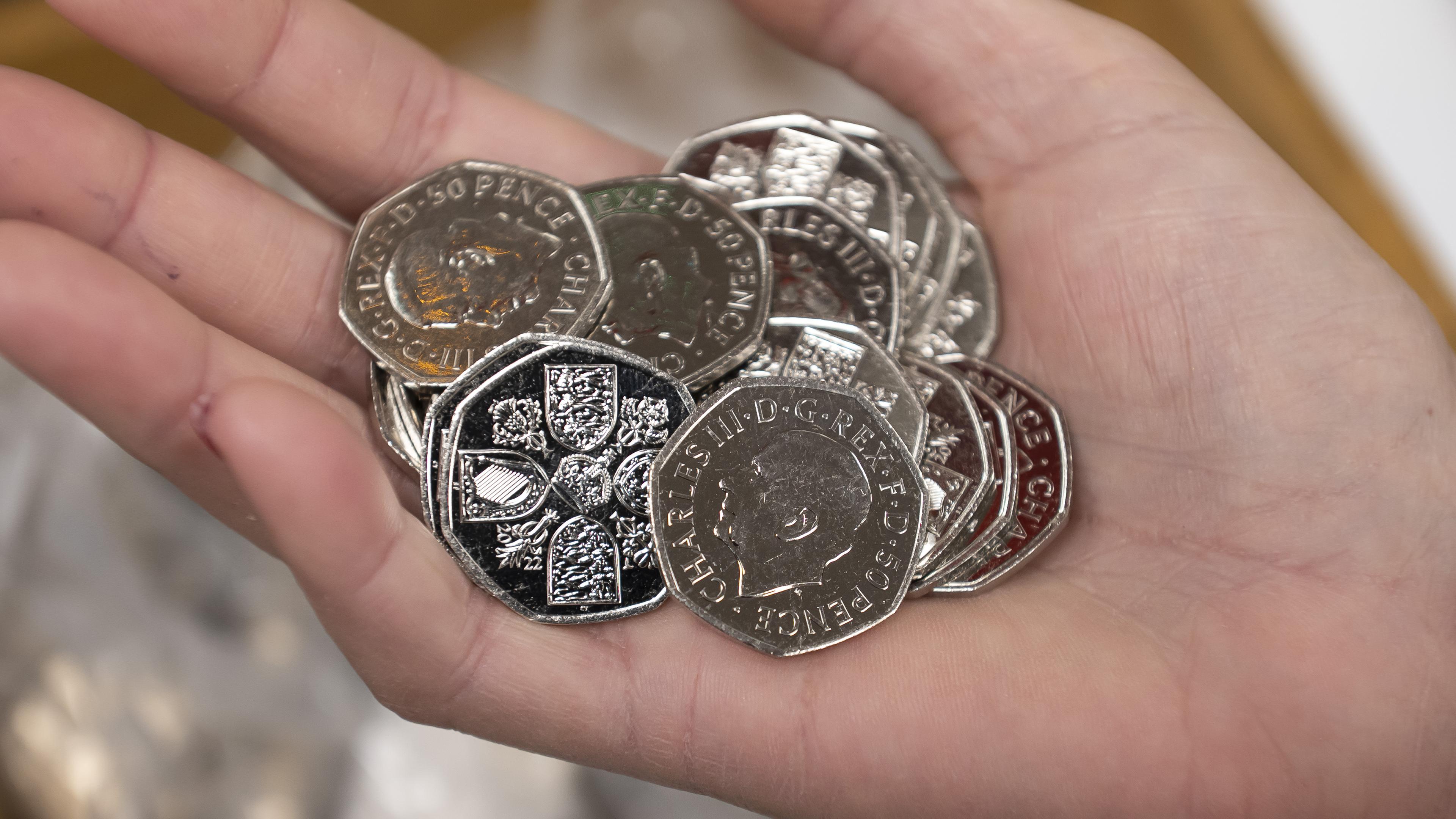 Eine Hand hält 50-Pence-Münzen mit dem Porträt von König Charles III.