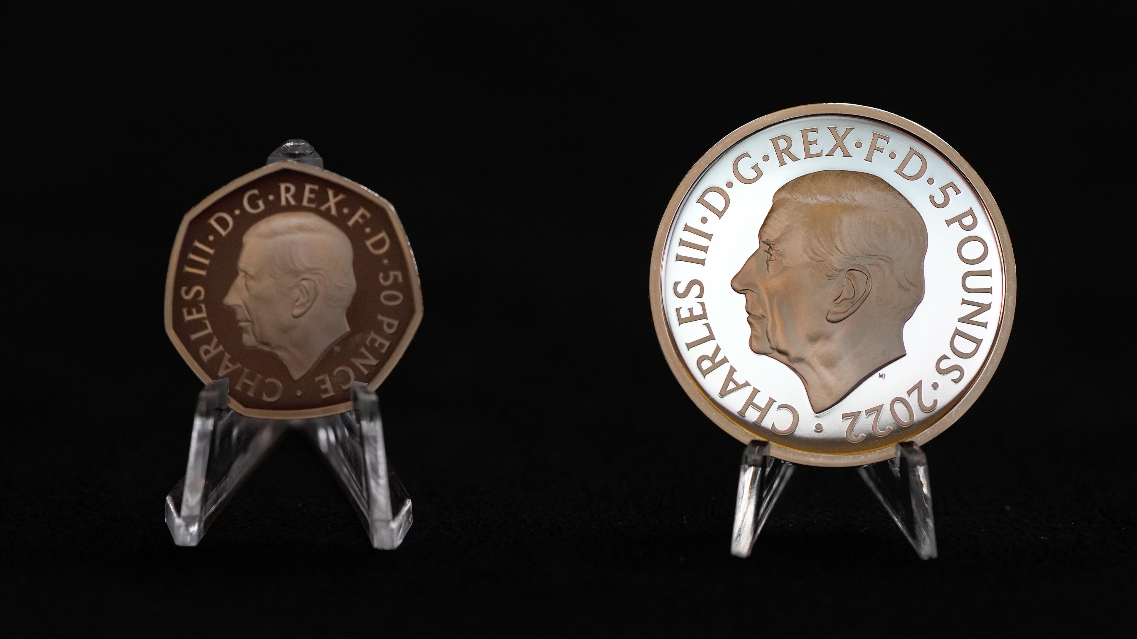 Großbritannien, London: Zwei neue Münzen mit dem Konterfei von König Charles III - links die neue 50-Pence-Münze und rechts die neue 5-Pfund-Gedenkmünze werden während einer Pressevorschau gezeigt.