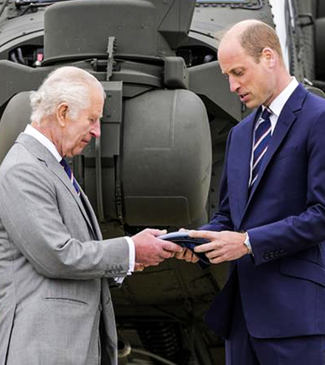 König Charles übergibt etwas an Prinz William 