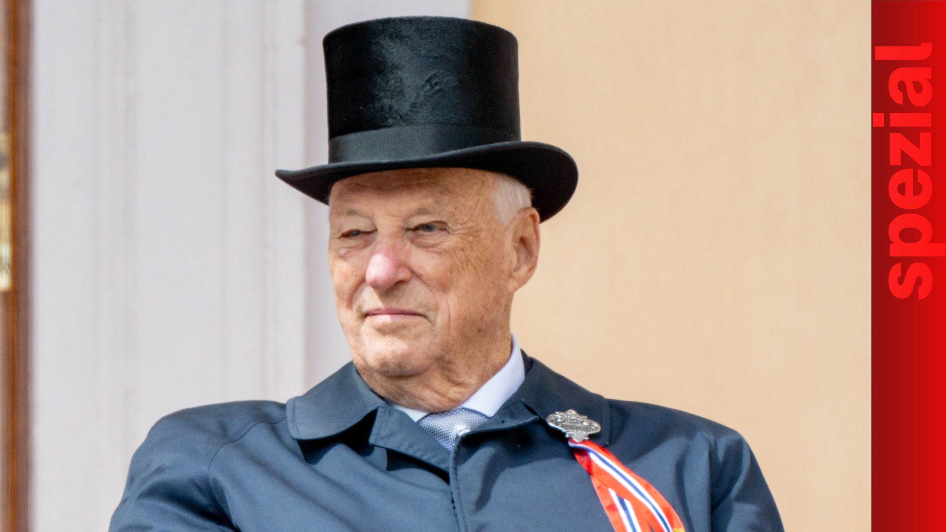 Auf dem Bild ist König Harald zu sehen. Er trägt einen schwarzen Zylinder und einen dunkelblauen Mantel mit einer rot-weiß-blauen Schleife.