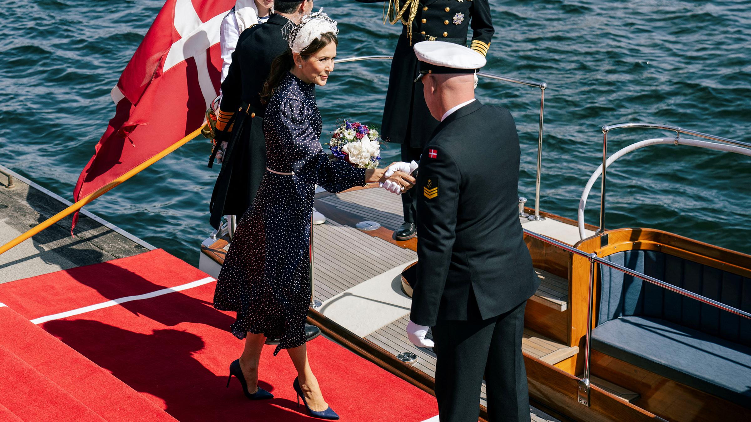 Königin Mary mit einem Kapitän auf einem Steg.