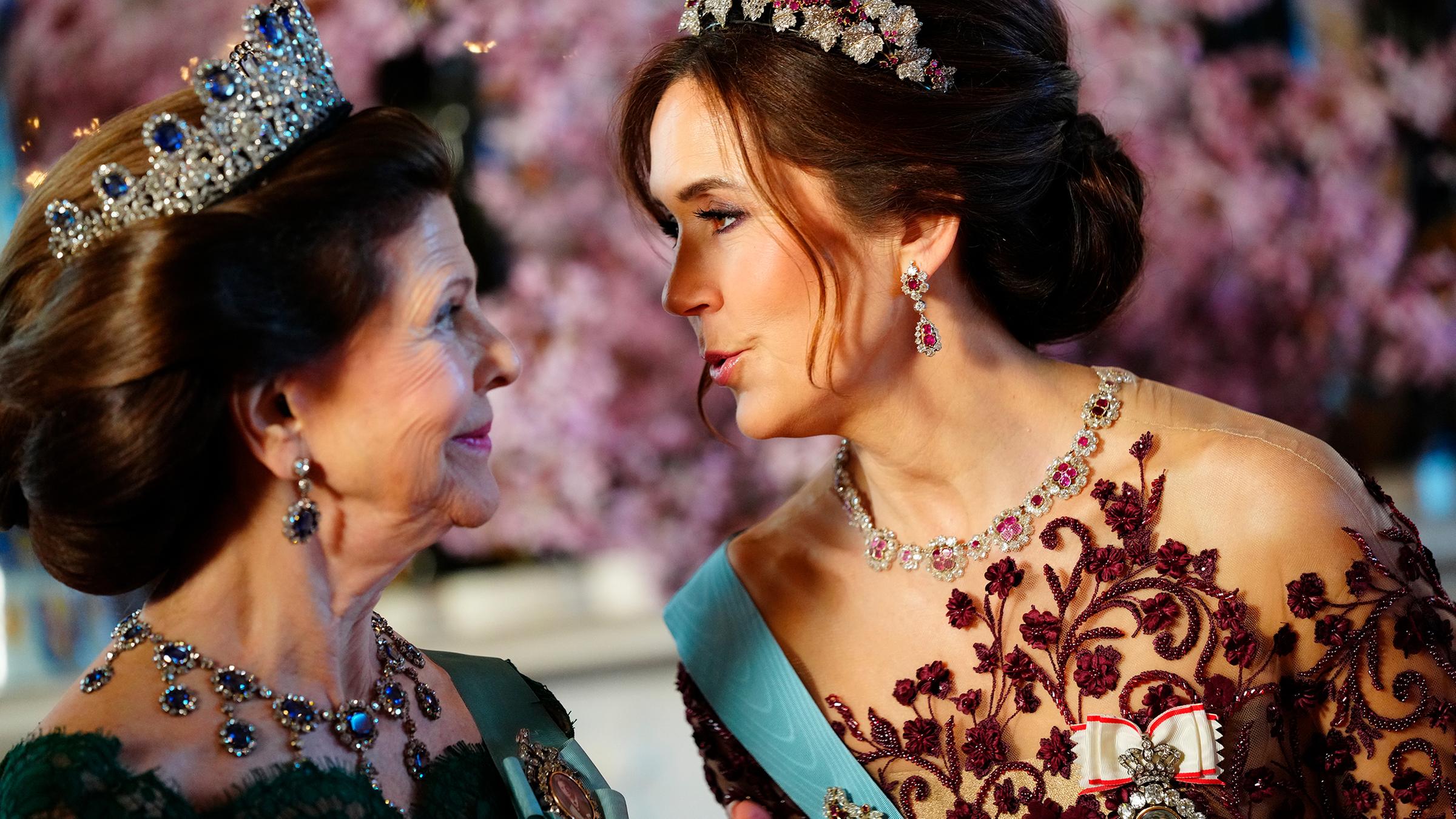 Königin Silvia und Königin Mary schauen sich gegenseitig an