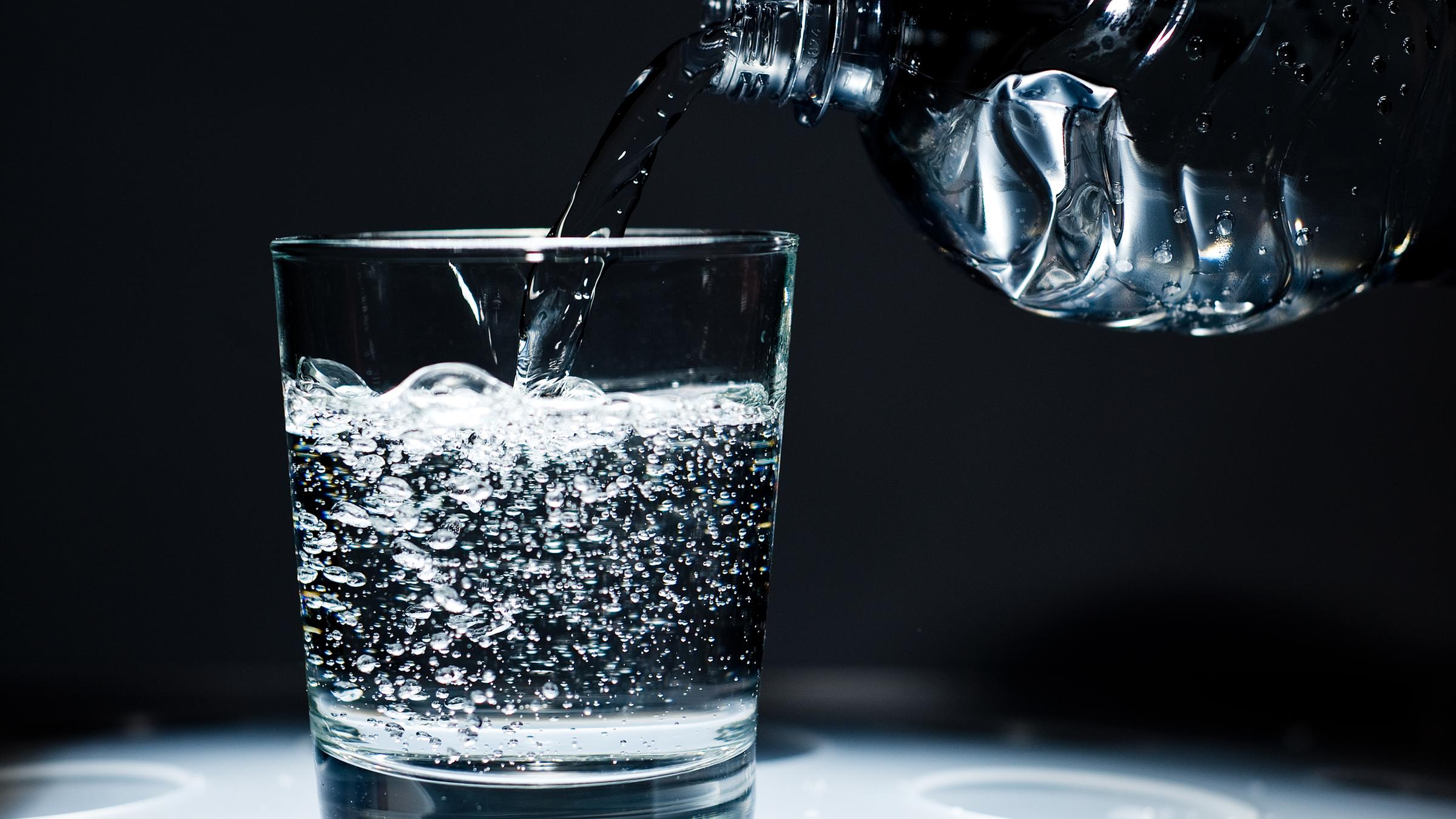 Ein Glas mit kohlensäurehaltigem Mineralwasser wird befüllt.