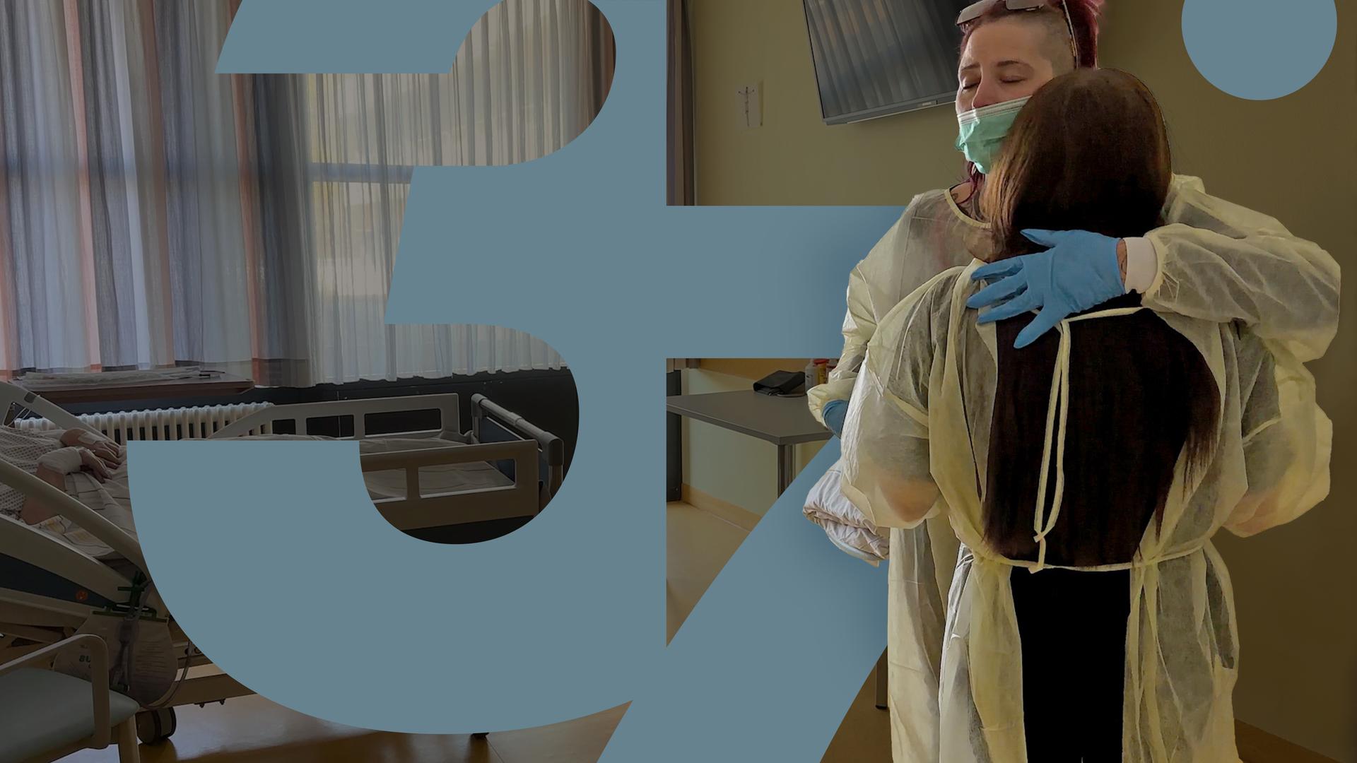 Im Bett eines Krankenzimmers liegt Doris. Ihre Tochter und ihre Enkelin stehen daneben, tragen Schutzkleidung und umarmen sich.