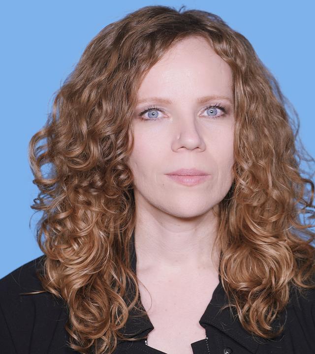 Sarah Bosetti befindet sich vor einem blauen Hintergrund. Rechts neben ihr steht "Grokipedia". In einer Sprechblase darunter steht "Kommentarspalte".