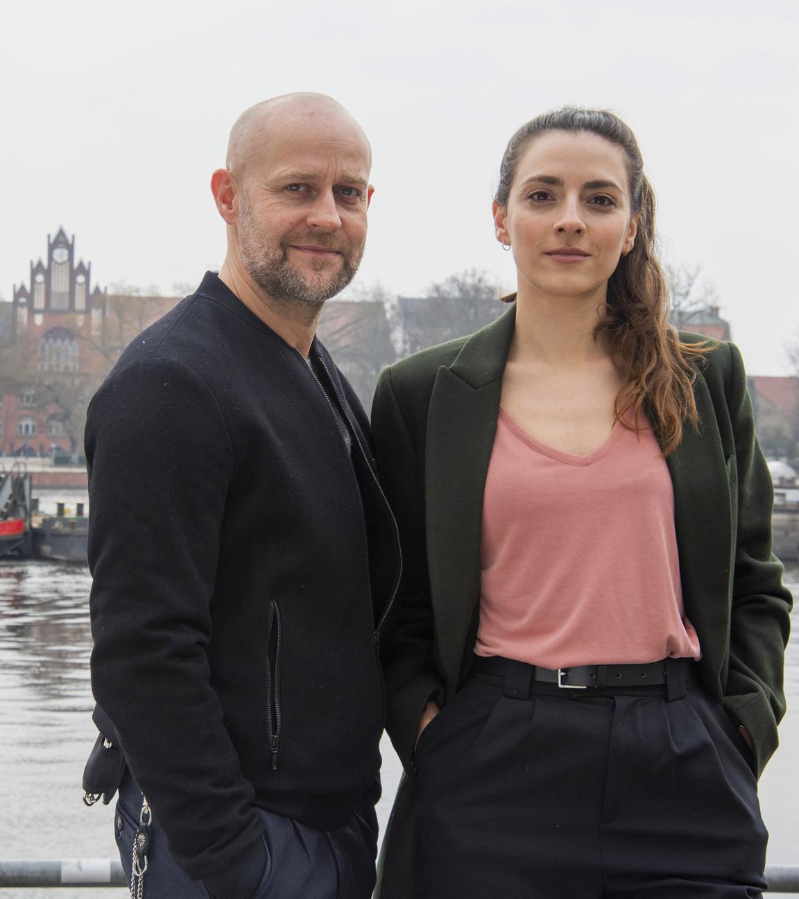 "Jenseits der Spree - Blutsbande": Kay Freund (Seyneb Saleh) und Robert Heffler (Jürgen Vogel) lehnen an einem Geländer an der Spree. Kay lächelt in die Ferne und Robert schaut zu ihr rüber.