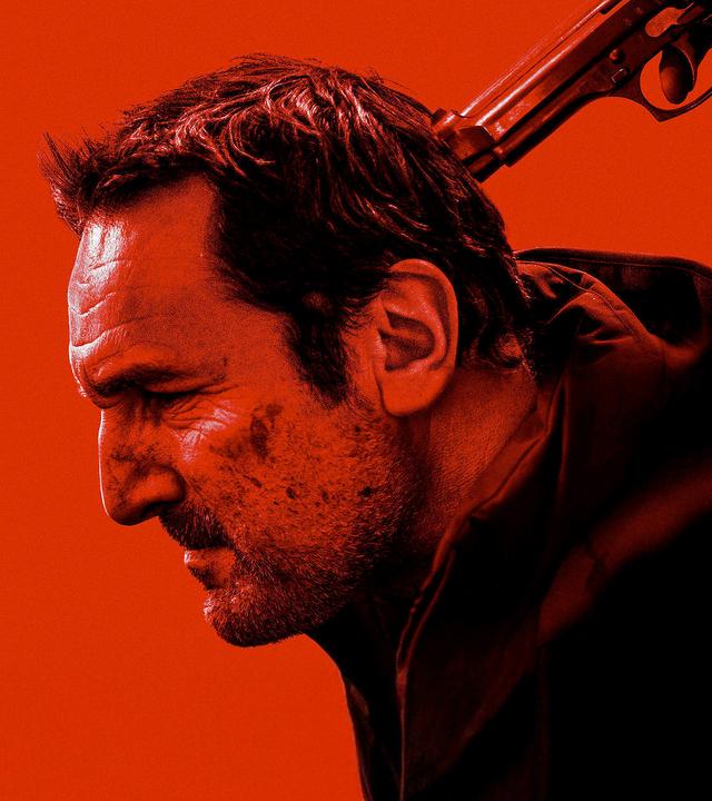 Schwarz-Rotes Foto: Blick von der Seite auf Mathieu Roussel (Gilles Lellouche), dem jemand hält eine Pistole an seinen Hinterkopf hält.