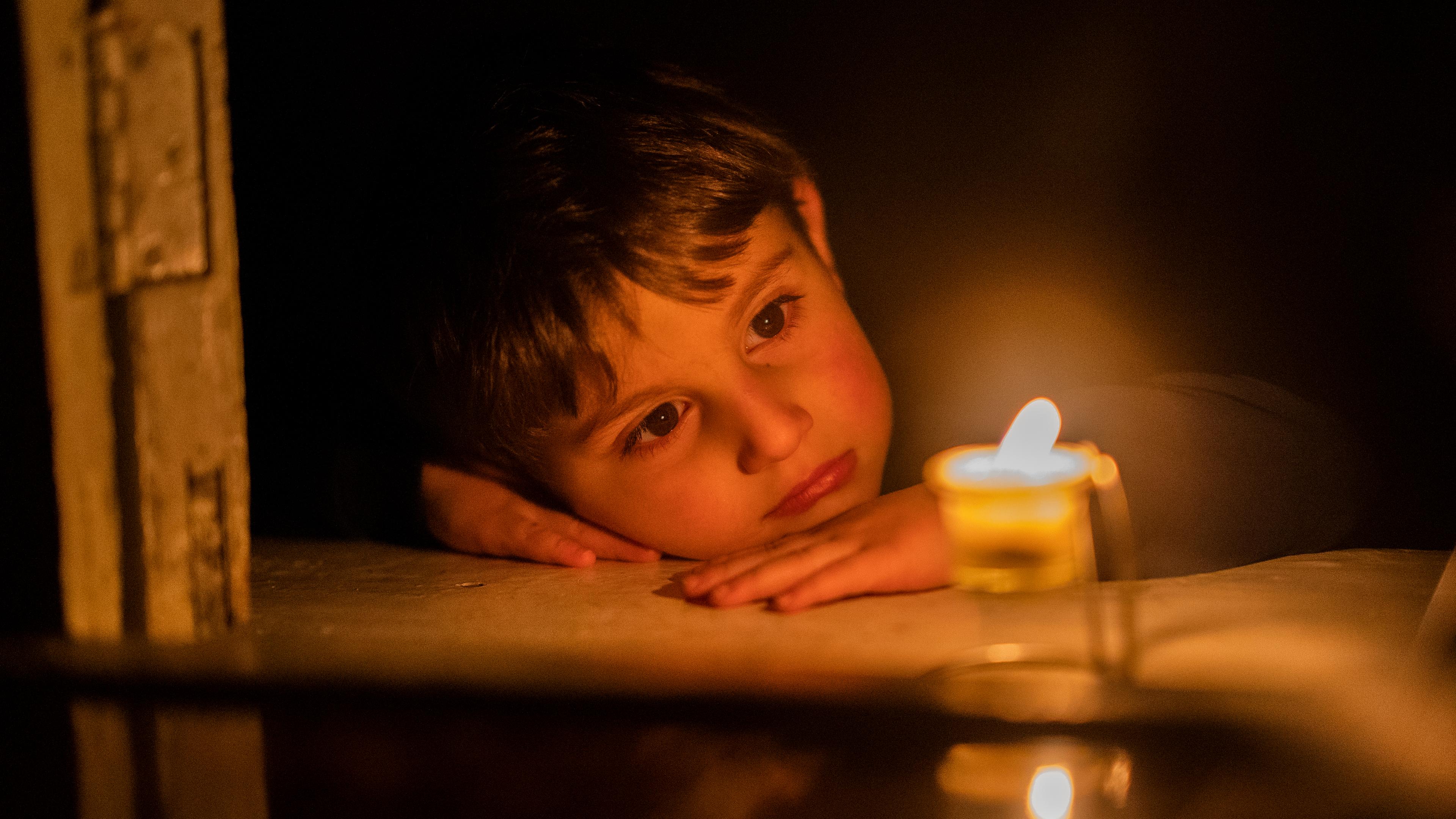 Aserbaidschan, Stepanakert: Ein Junge schaut auf eine Kerze, um sich zu Hause in Stepanakert, der Hauptstadt der separatistischen Region Berg-Karabach, auch bekannt als Artsakh, zu wärmen.