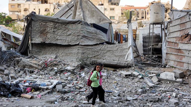 Kinder gehen vor einem Wohngebäude entlang, das am Vortag bei einem israelischen Angriff im Viertel Rimal in Gaza-Stadt getroffen wurde.