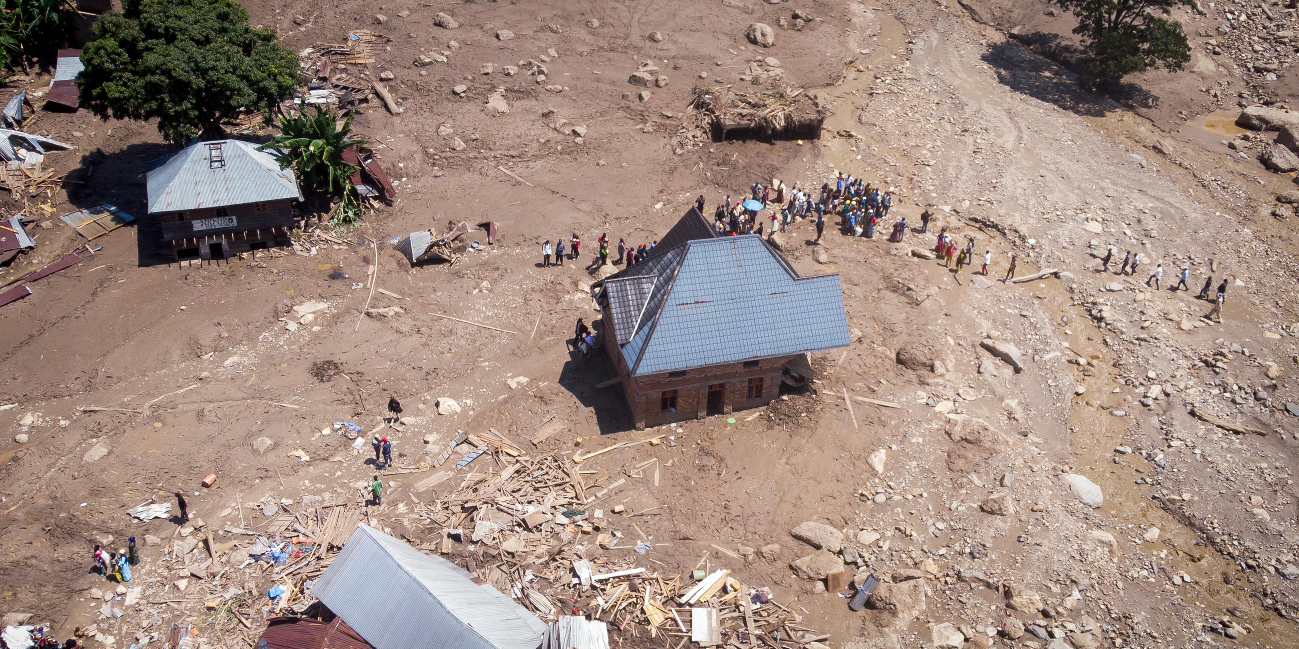 Luftaufnahme von Überlebenden zwischen den Trümmern zerstörter Gebäude nach einer Überschwemmung in einem Dorf im Kongo.