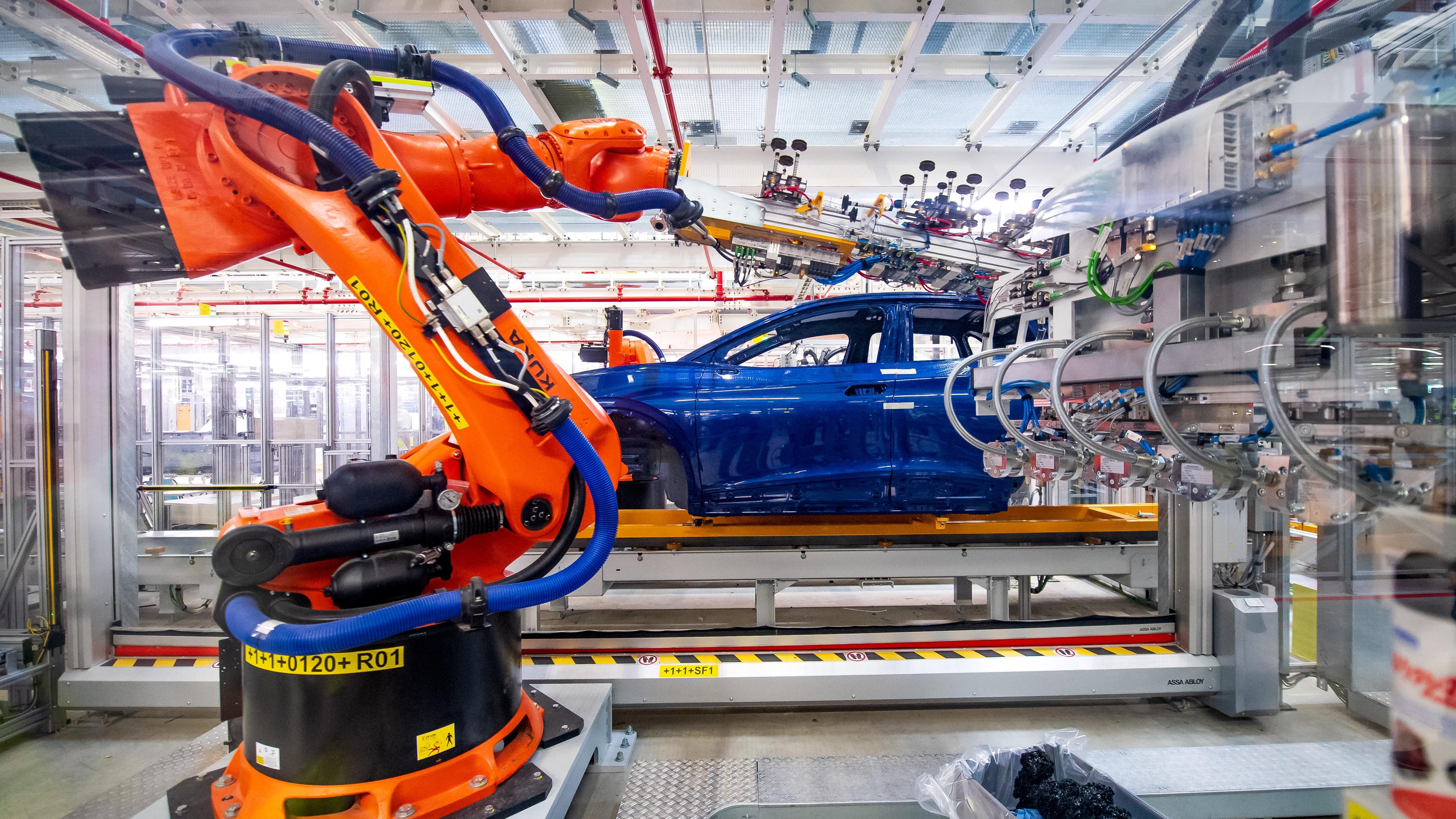 Ein Roboter motiert ein VW-Werk Bauteile.