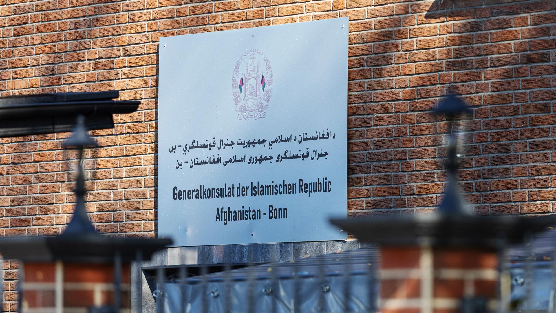 Ein Schild mit Informationen hängt an einer Hauswand.