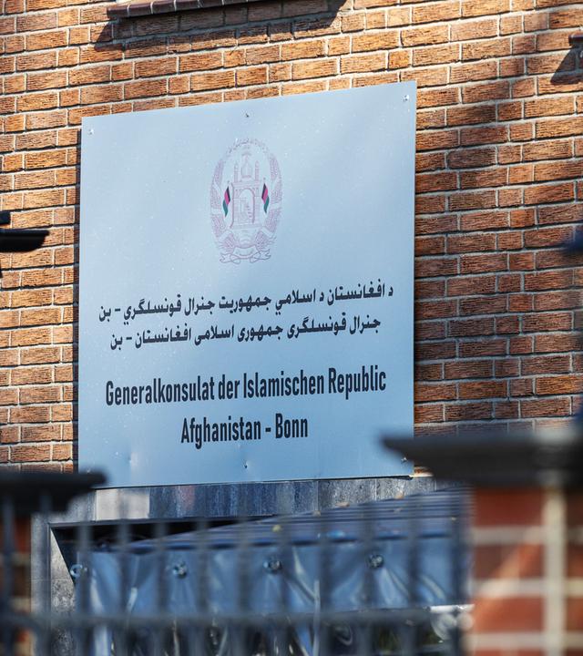 Ein Schild mit Informationen hängt an einer Hauswand.