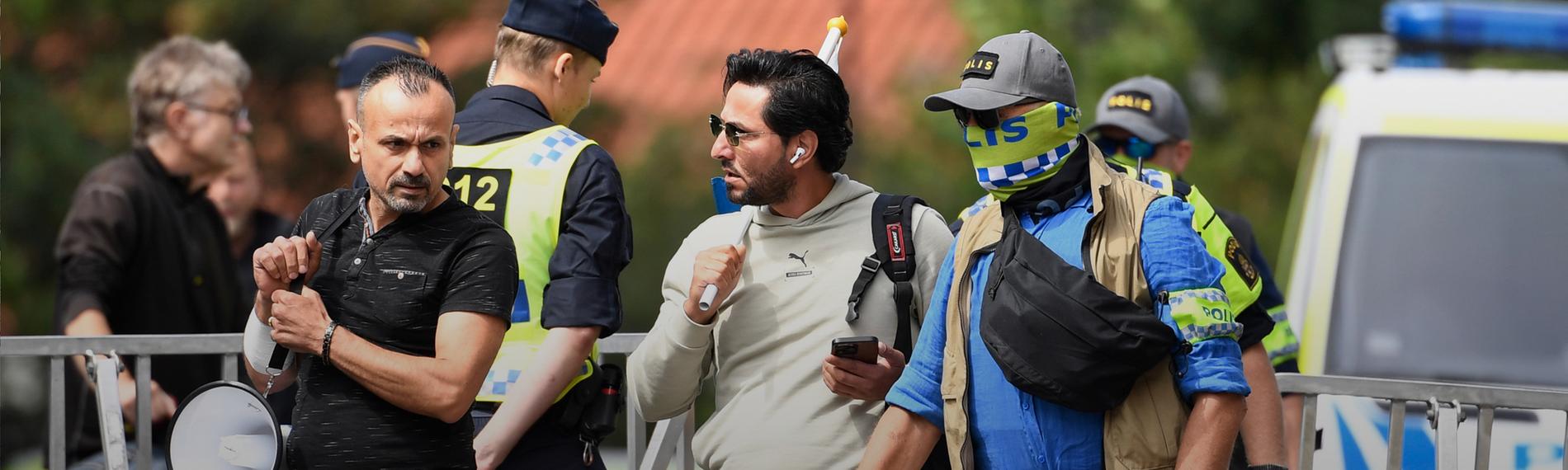 Salwan Momika (Mitte) wurde von Polizisten zu einem Ort seiner Demonstration vor der irakischen Botschaft in Stockholm eskortiert.